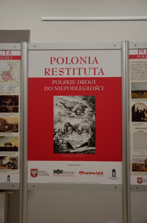 biało czerwony plakat wystawy na tle plansz