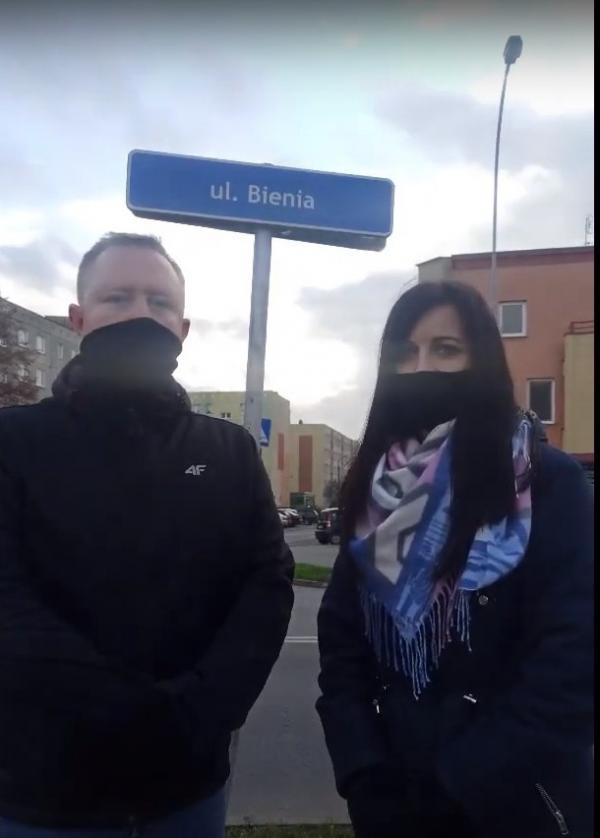 dwie osoby na tle tablicy informacyjnej