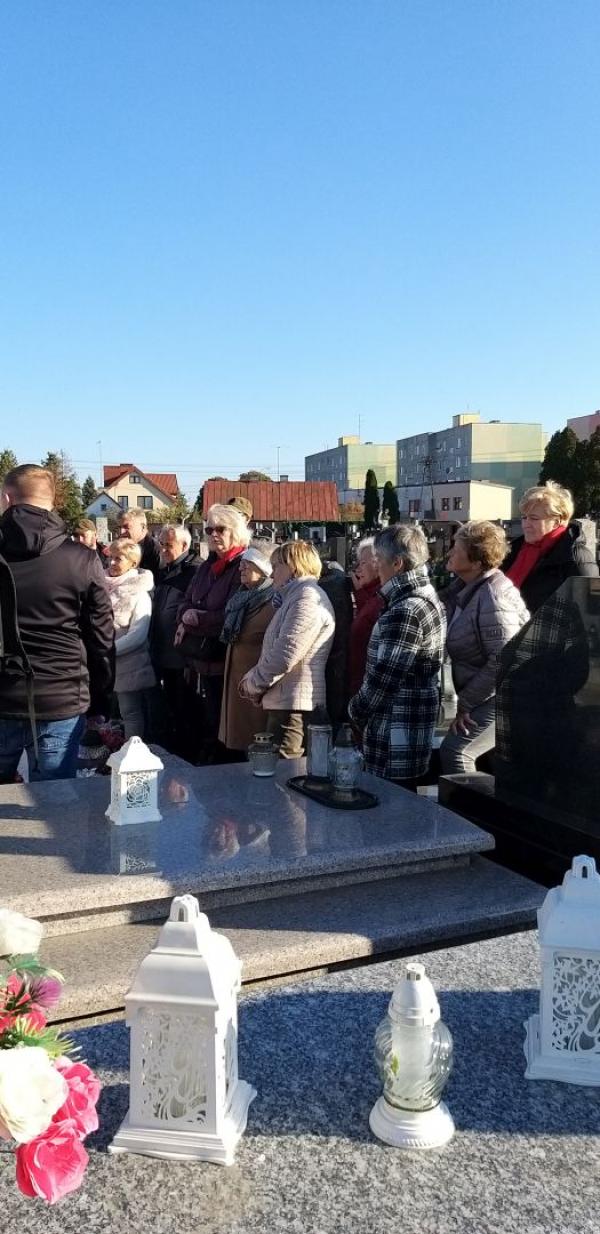 Grupa osób stojących na cmentarzu